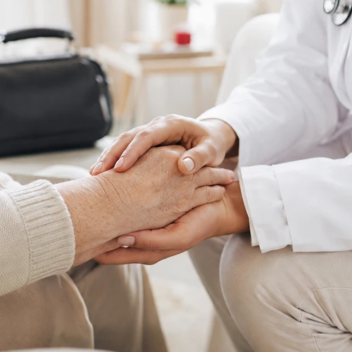 Ärztin Hält Hände älterer Patientin