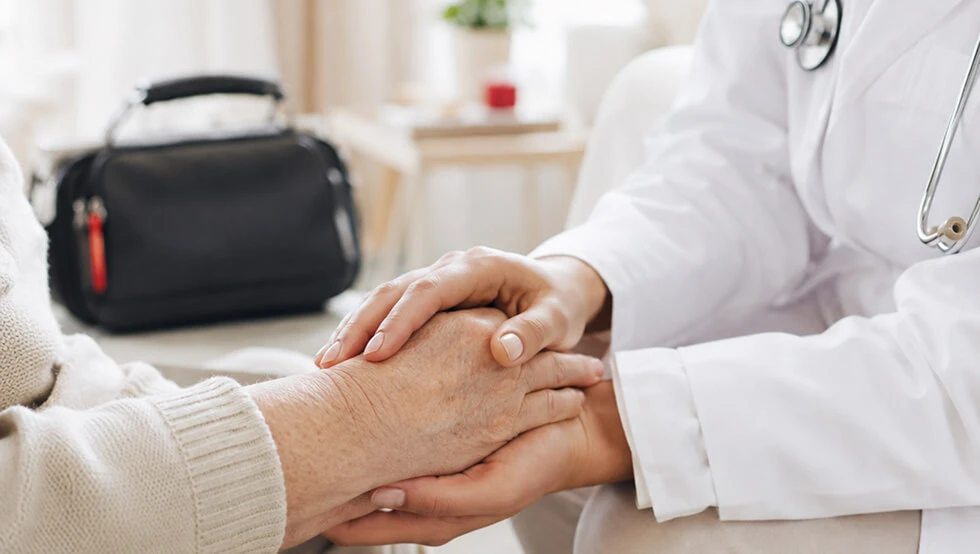 Ärztin Hält Hände älterer Patientin